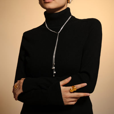Steel multi-strand lariat with pearl drops worn on black turtleneck