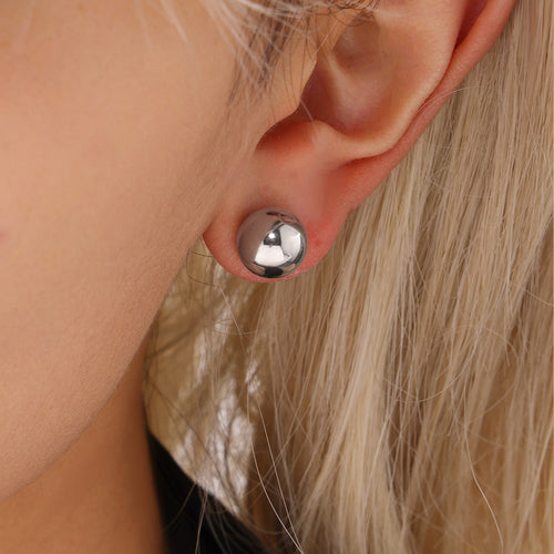 Silver steel hollow ball stud earring close-up on ear
