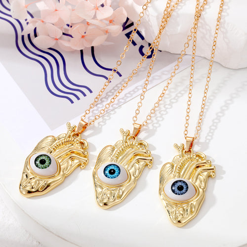 Three gold anatomical heart eye pendants green blue and gray irises on chains