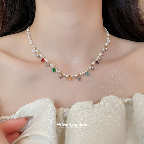 Close display of a white pearl-like strand accented by scattered bright beads and tiny gold tone charms