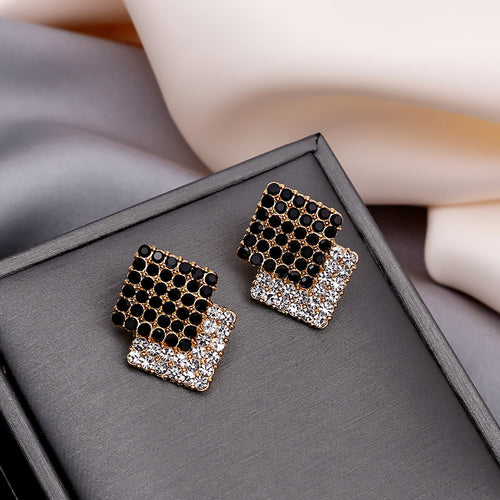 Black and clear crystal overlap square gold studs on gray box
