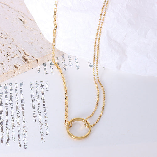 Gold dual-chain circle connector necklace flat lay on book page