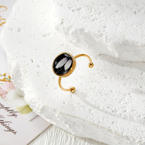 White petal dried flower black cabochon gold open ring on white stone