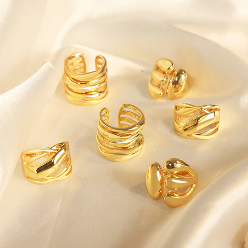 Six gold open statement rings scattered on white silk