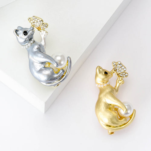 Gray and gold pearl cat butterfly brooches on white platforms