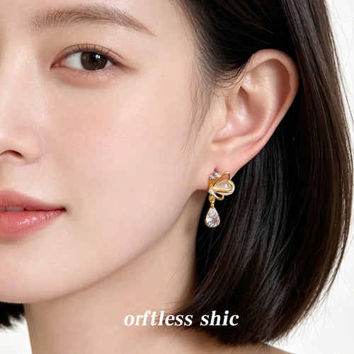 Gold cream butterfly clear drop stud worn on ear close-up
