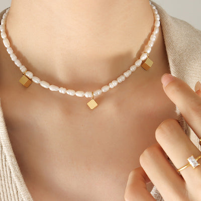 Model wearing baroque pearl necklace with three gold cube charms