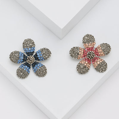 Grouped view of five-petal gray crystal flower brooch with colored bands arranged together.
