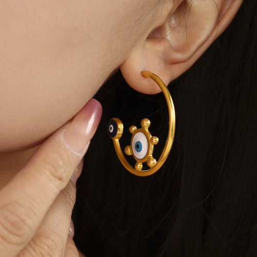 Close-up gold C-hoop earring with enamel eye on ear