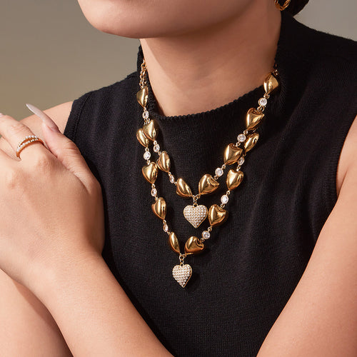 Gold heart necklace layered with pearl strand on model