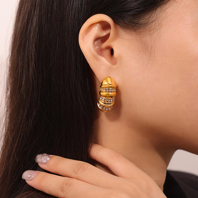 Model wearing gold ribbed capsule stud earring with rhinestone bands