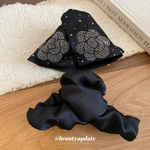black fabric flower crystal embellished claw hair clip shown in an on-ear styling view
