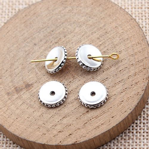 Antique Silver Smooth Disc Spacer Beads for Jewelry Making arranged on a wood slice