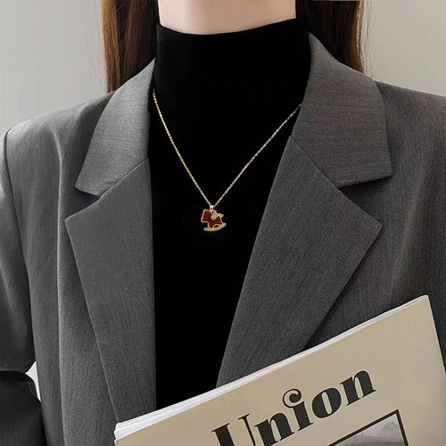 Gold red enamel rocking horse pendant necklace worn on black turtleneck