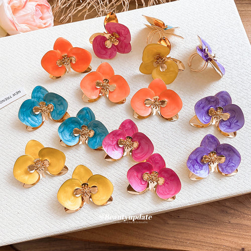 Assorted color orchid flower earrings and rings on white board