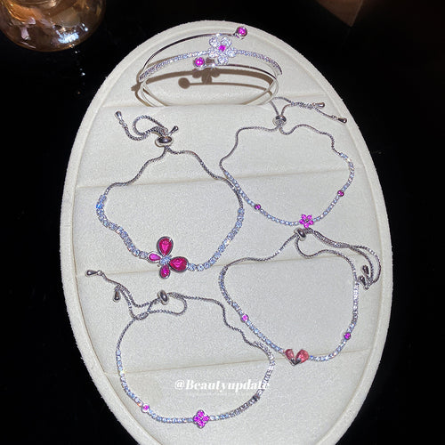 Silver magenta butterfly and flower bracelets arranged on cream display pad