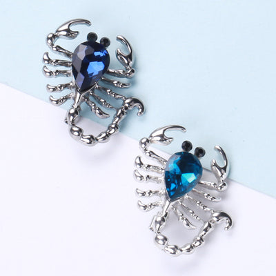 Teal and navy silver crystal scorpion brooches on dual background