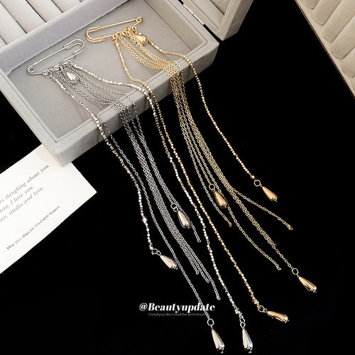 Gold and silver multi-chain tassel brooches in open gray box