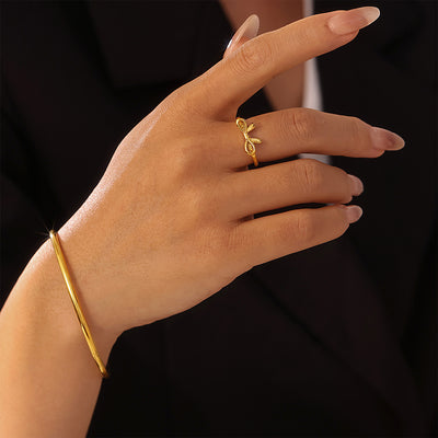 Gold bow ring and gold bangle worn together on model hand