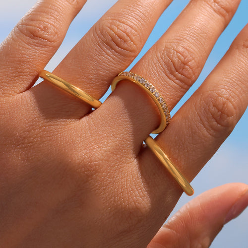 Close-up gold triple stack ring with zircon row on finger against sky