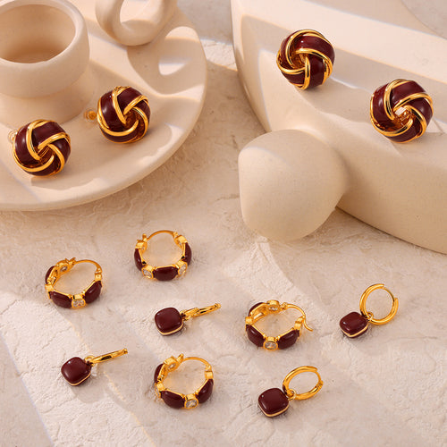 Assorted gold burgundy oil-drip earrings including knot studs hoops and drops