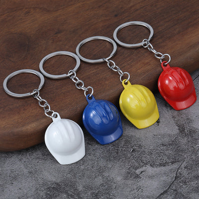 Four miniature helmet keychains in white, blue, yellow, and red displayed together.