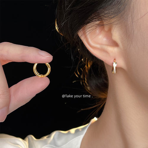 Gold-tone double-line round huggie hoops shown worn on an ear.