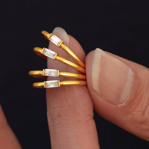 Styled hand view of gold tone rectangular solitaire slim ring in main image 1.
