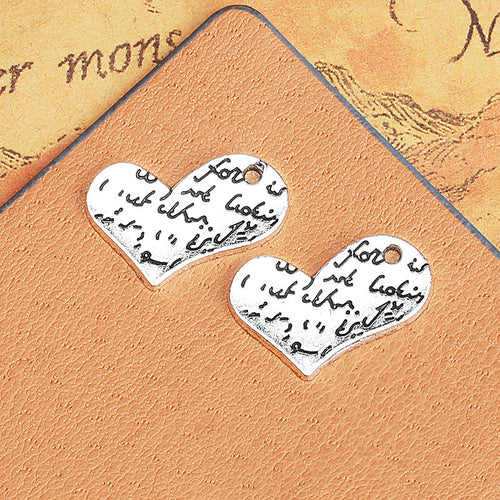 A flat heart charm printed with a handwritten-style love message displayed from a second angle