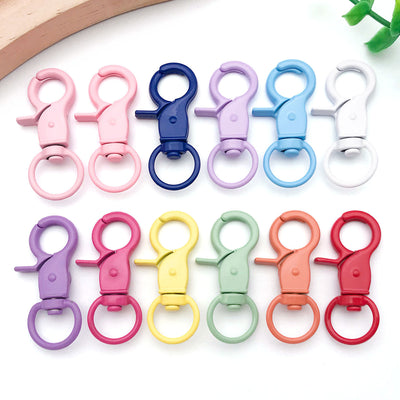 Colorful swivel clasp jewelry findings arranged on a light background