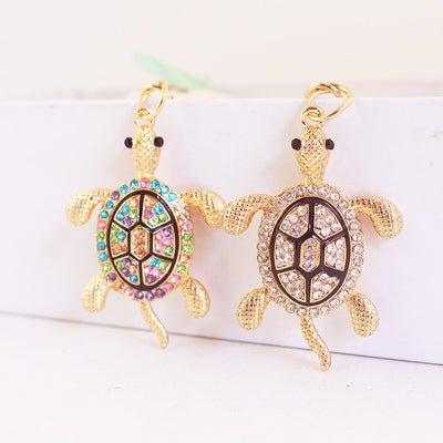 Clear and multicolor rhinestone sea turtle pendants shown side by side.