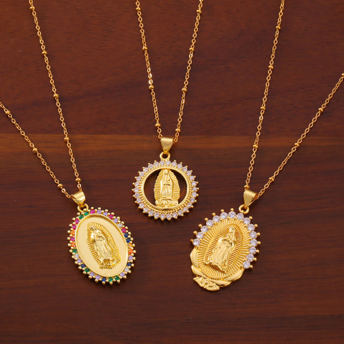 Three gold religious figure pendants laid on wood table
