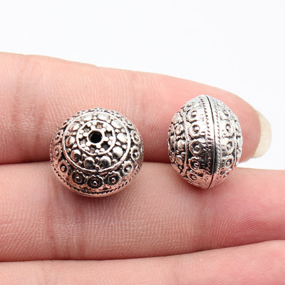 Front fingertip view of 镂空花纹球形珠 showing its visible shape and finish