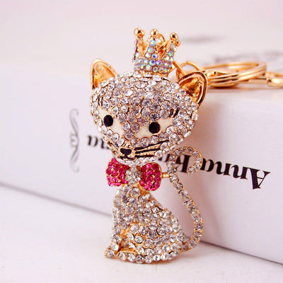 Close-up of the crowned cat keychain with clear stones and a bright pink bow tie.
