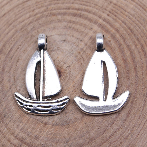 Antique Silver openwork sailboat charm displayed on a wood and linen setting