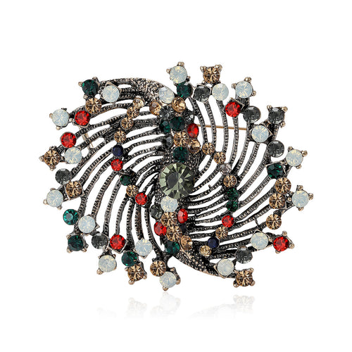 Front view of a coiled circular brooch with mixed red green and clear bead accents