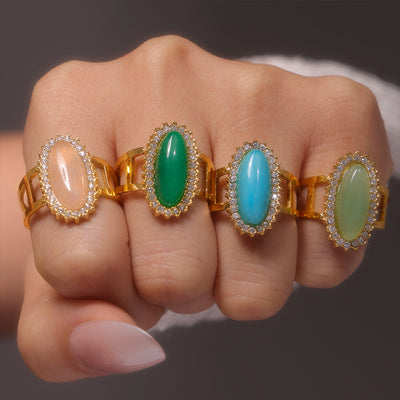 Four gold oval natural stone halo rings worn across knuckles