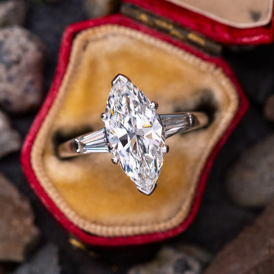 Product view showing silver-tone marquise clear solitaire baguette three-stone ring