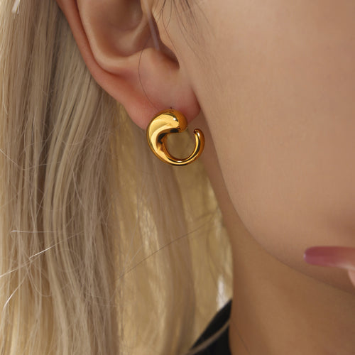 Close side view of gold swirl teardrop stud earring on ear