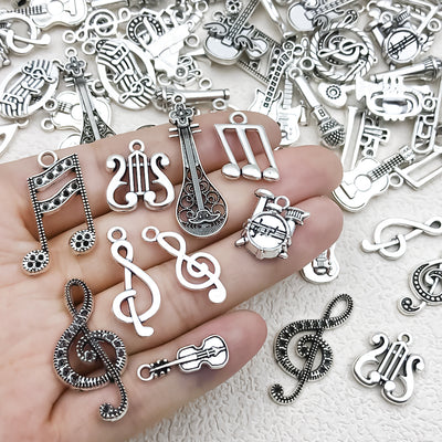 Antique silver musical instrument and guitar charms arranged on a light background