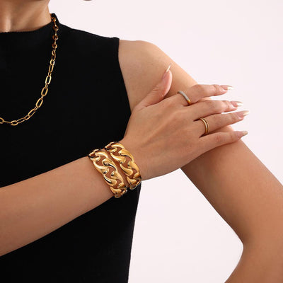 Model wearing two gold open teardrop Cuban link cuff bangles