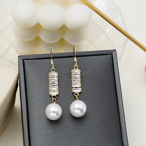 Gold tone baguette crystal bar pearl drop earrings on black display pad