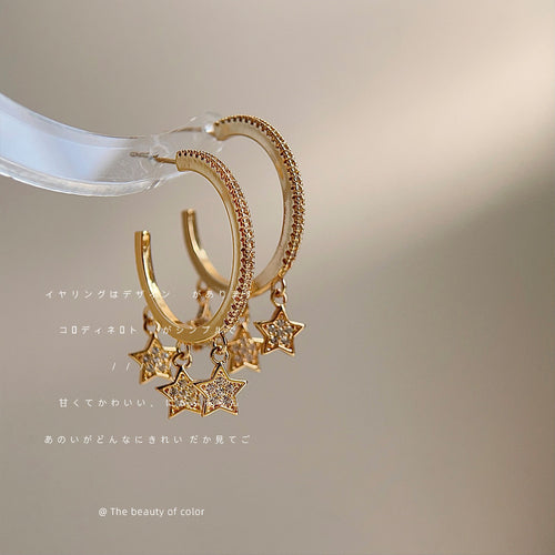 Gold paved hoop multi star drops on clear rod black bg