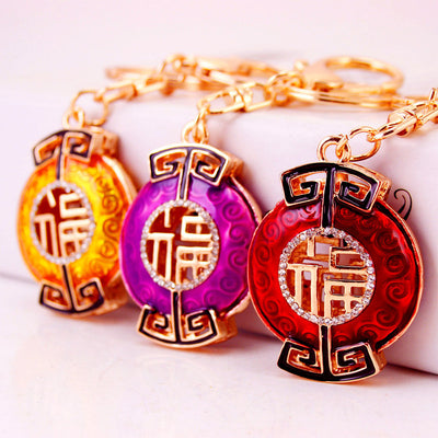 Three Fu character keychains in gold, purple, and red are displayed together.