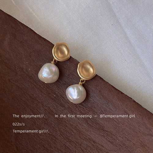 Matte-gold irregular-square baroque-white-pearl earrings shown worn on an ear.