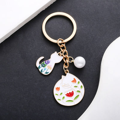 Front product photo of white cat flower and pearl enamel charm keychain with round ring showing the pictured design arra