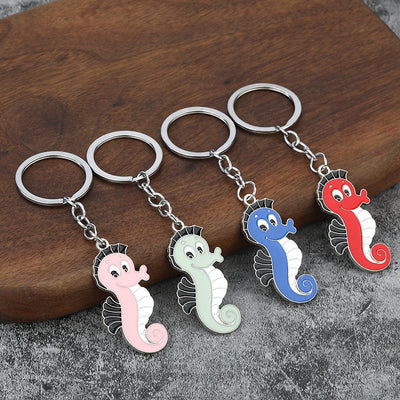 Four colorful seahorse keychains arranged beside a wooden block.