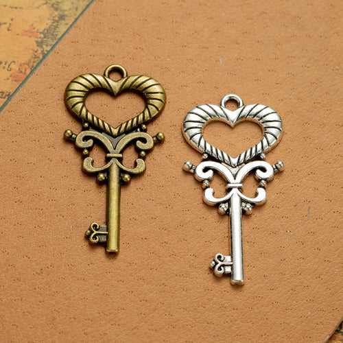 Main product image of the ornate heart skeleton key pendant showing a long key topped by a ribbed open heart and scrollw