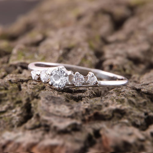 Side angle of slim five-stone silver-tone ring on textured rock