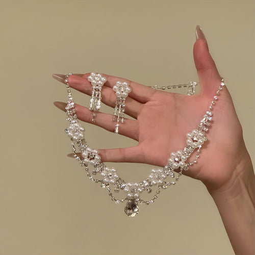 Pearl flower necklace and tassel earrings held in open hand